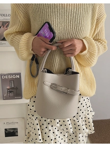 Detail of off-white bucket bag featuring lychee texture leather and silver metal buckle