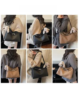 Detailed view of leather hobo bag with signature lock closure and plush charm