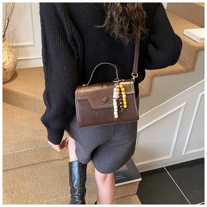Brown vintage leather shoulder bag with colorful beads on stylish model on stairs