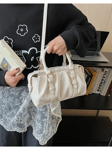 Detailansicht der cremefarbenen Faltenhandtasche mit vertikalen Falten und Goldring