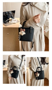 Detail of black pebbled leather bucket bag with top handle and cute bear charm pendant