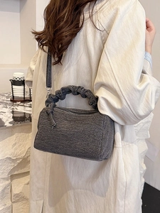 Sac polochon en tissu gris foncé avec poignée plissée et bandoulière sur mannequin