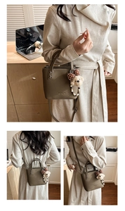 Detail of lychee pattern leather bucket bag with dog plush charm and branding