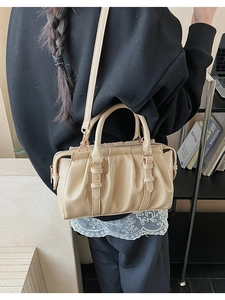 Detail of apricot pleated handbag with gold hardware shown in a lifestyle setting