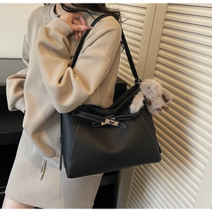 Detail of black lychee grain leather tote bag with white stitching and plush rabbit charm