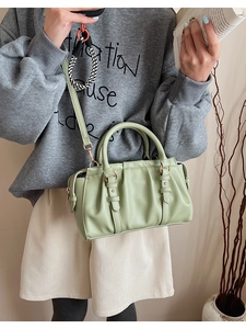 Detail of light green pleated handbag featuring elegant golden metal handles and strap