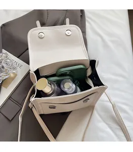 Detail view of the spacious inner compartment of this beige square crossbody bag
