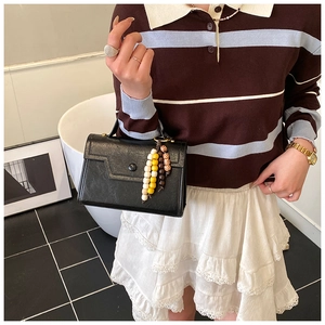 Detail view of a black crossbody bag with decorative multi-color wooden bead tassel