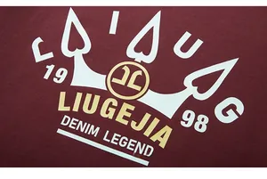 Detail of crown and logo print on burgundy oversized long-sleeved t-shirt fabric