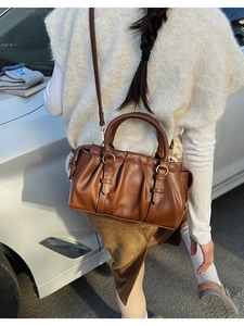 Close-up of caramel brown pleated bag with gold ring details and adjustable strap