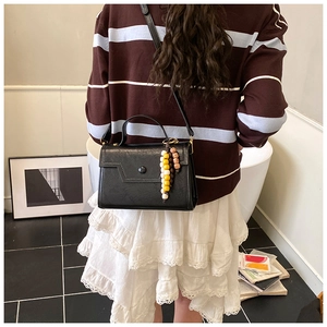 Black leather crossbody bag with long shoulder strap and colorful beaded tassel detail