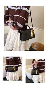 Detail of black vintage leather mini box bag with decorative yellow bead charm