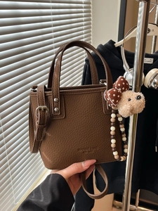Brown litchi texture bucket bag with dual handles and a cute plush bear charm