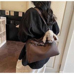 Detail of dark brown lychee grain leather handbag with metal buckle and rabbit charm