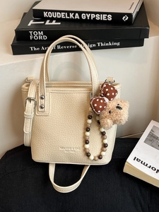 Minimalist beige lychee leather bucket bag with cute plush bear and shoulder strap