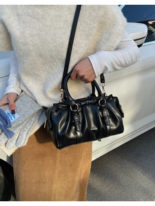 Detail of black ruched handbag showing premium texture and gold metal ring hardware