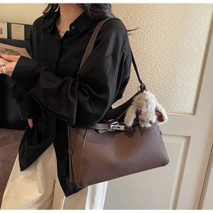 Detail of brown litchi leather handbag with silver buckle and plush rabbit charm
