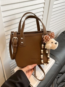 Brown litchi leather bucket bag with dog pendant and adjustable shoulder strap