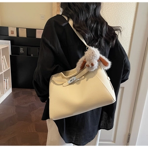 Detail of beige pebbled leather shoulder bag with buckle and plush rabbit charm