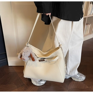 Close-up of beige lychee grain leather tote with silver twist lock and plush rabbit charm