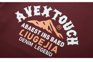 Detail of white AVEXTOUCH lettering and orange mountain print on burgundy cotton t-shirt