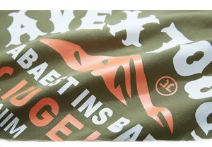 Detail of army green cotton t-shirt fabric with orange and white artistic screen print