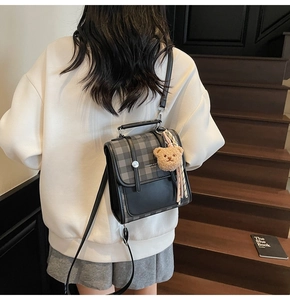 Detail of plaid crossbody bag featuring a plush bear charm and tassel on the side