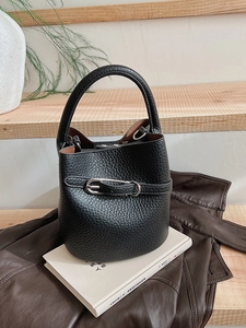 Classic black lychee pattern leather bucket bag with silver buckle on a white book
