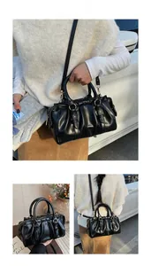 Detailansicht einer schwarzen Falten-Tote-Bag mit goldenen Beschlägen und Schultergurten