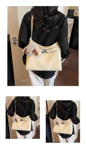 Close-up of cream leather shoulder bag with metallic buckle and plush rabbit charm