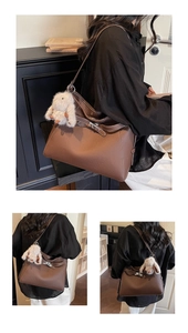 Detail of brown litchi pattern leather bag with white stitching and rabbit charm