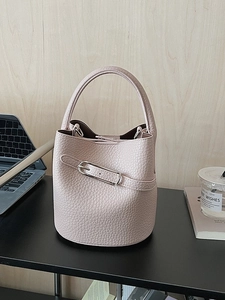 Elegant beige lychee grain bucket bag on a desk for urban commuting fashion