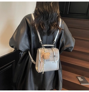 Silver leather backpack detail featuring a plush bear charm and pink tassel decoration