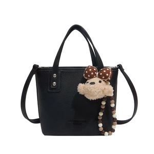 Classic black bucket bag in lychee leather with plush animal charm and beaded detail