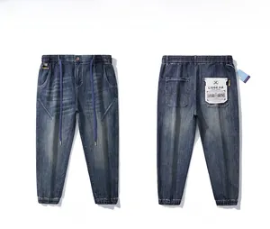 Detail of blue washed denim joggers with elastic drawstring waist and cuffed ankles