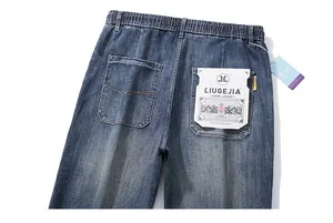 Detail of elastic waistband and large decorative pocket patch on washed blue denim pants