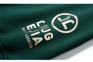 Macro detail of gold foil lettering and fiber texture on dark green knit sweatshirt