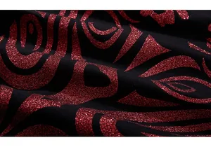 Détail macro de l'imprimé pailleté rouge sur le tissu en coton noir du t-shirt oversize