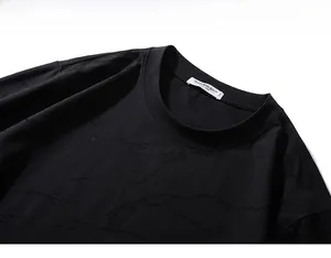Detail of black crew neck T-shirt with textured embossed fabric and interior size label