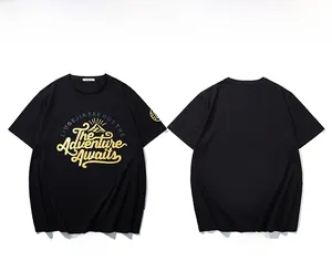 Detail eines schwarzen Baumwoll-T-Shirts mit goldenem 'The Adventure Awaits' Bergdruck
