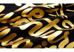 Makroaufnahme von hochwertigem Gold-Metallic-Foliendruck auf schwarzem Baumwollstoff
