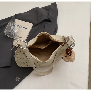 Dettaglio borsa a spalla beige a pois con cerniera e ciondolo a forma di cagnolino