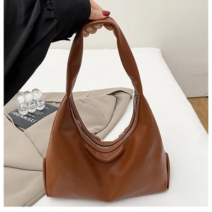 Détail d'un sac hobo en cuir marron avec large bandoulière et fermeture à glissière