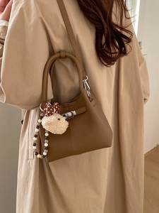 Borsa a secchiello in pelle marrone con manico e ciondolo di peluche elegante