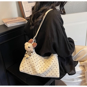 Dettaglio di una borsa a pois bianco crema con un simpatico ciondolo a forma di orsetto