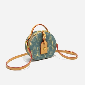 Dettaglio della borsa tonda in denim vintage con motivi floreali e tracolla in pelle