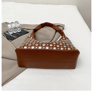 Détail du sac seau vintage en cuir marron avec décoration de rivets argentés denses