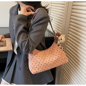 Borsa a spalla rosa a pois con ciondolo a orsetto indossata su un blazer grigio