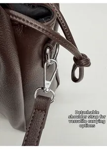 Détail du fermoir pivotant argenté et de la bandoulière sur un cabas en cuir marron