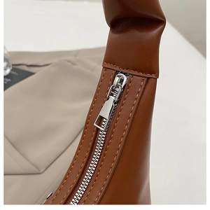 Gros plan détaillé sur le zip argenté et les coutures du sac hobo en cuir marron